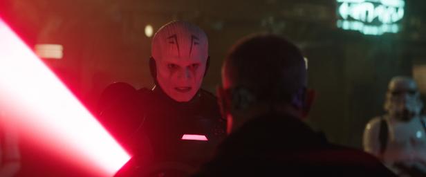 Der Großinquisitor mit einem roten Lichtschwert im Gespräch mit einer Person; im Hintergrund ein Stormtrooper.