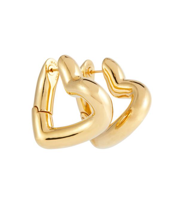 Nahaufnahme von zwei goldenen, herzförmigen Ohrringen.