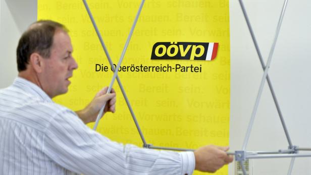 Ein Mann baut einen Stand der ÖVP Oberösterreich auf.