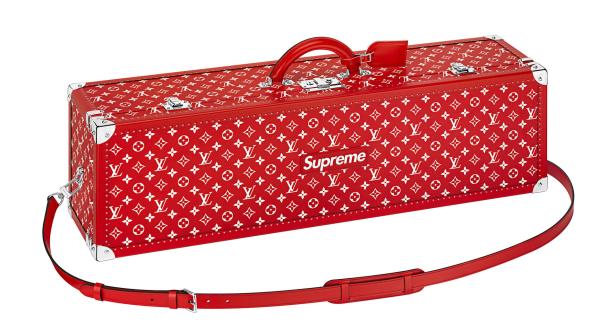 Ein roter Louis Vuitton x Supreme Koffer mit Trageriemen.