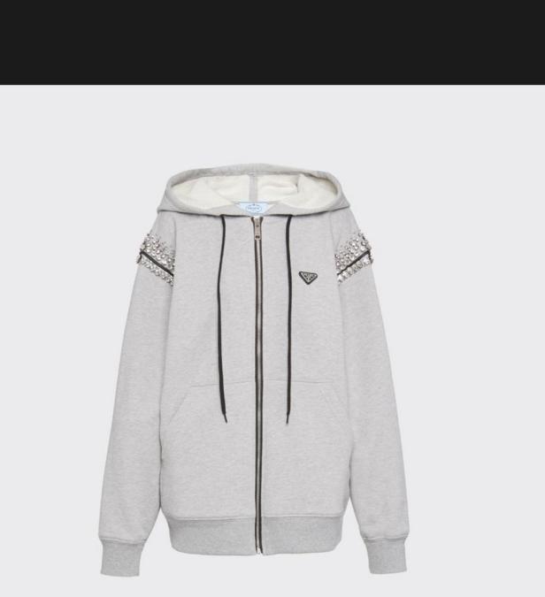 Ein grauer Prada-Hoodie mit Reißverschluss und Strassapplikationen an den Schultern.