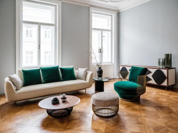 Ein Wohnzimmer mit einem Sofa, einem Sessel und einem Couchtisch auf einem Parkettboden.
