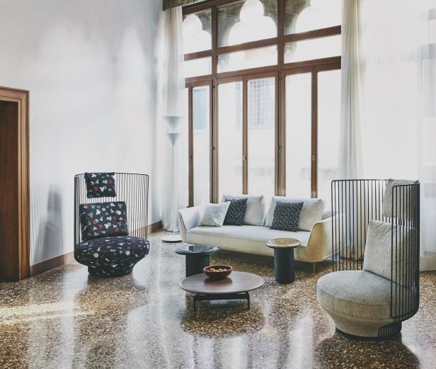 Ein Wohnzimmer mit einem Sofa, zwei Sesseln und einem runden Tisch auf einem Terrazzoboden.