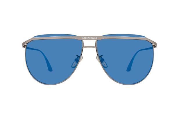 Eine silberne Balenciaga-Sonnenbrille mit blauen Gläsern vor einem weißen Hintergrund.