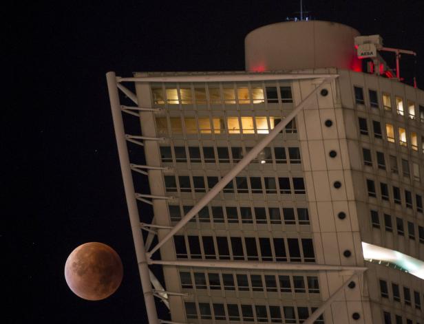 Der Turning Torso in Malmö mit einer rötlichen Mondfinsternis im Nachthimmel.
