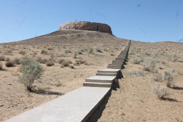 Eine lange Treppe führt zu einer Festung auf einem Hügel in einer Wüstenlandschaft.