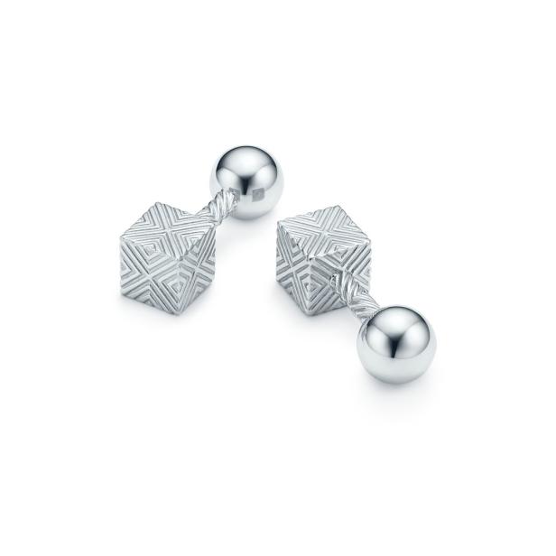 Zwei silberne Manschettenknöpfe mit Würfel- und Kugeldesign auf weißem Grund.