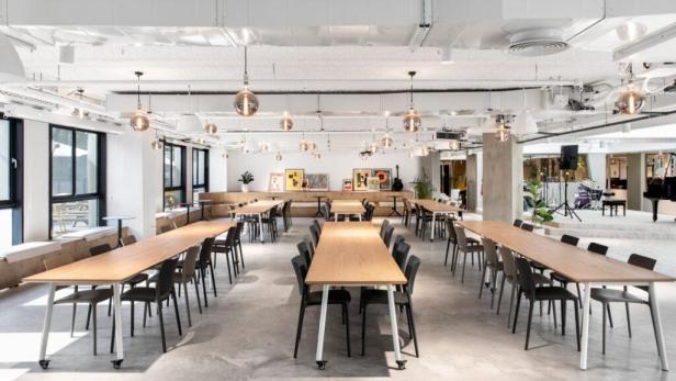 Ein großer, heller Raum mit langen Tischen und Stühlen, geeignet für Veranstaltungen.