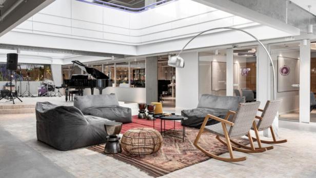 Ein offener Büroraum mit Sitzgelegenheiten und einem Klavier auf einer Bühne.