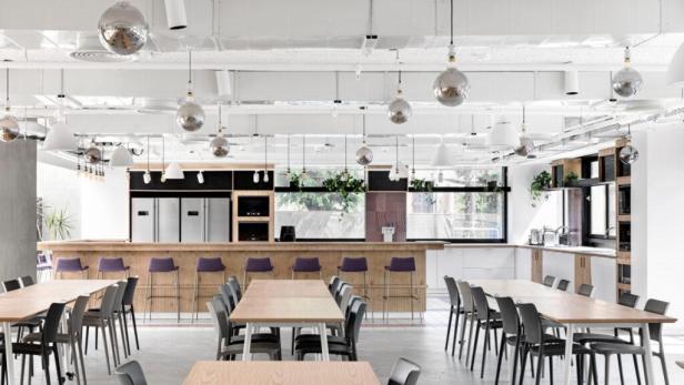 Ein großer Büroraum mit Tischen, Stühlen, einer Bar und Discokugeln an der Decke.