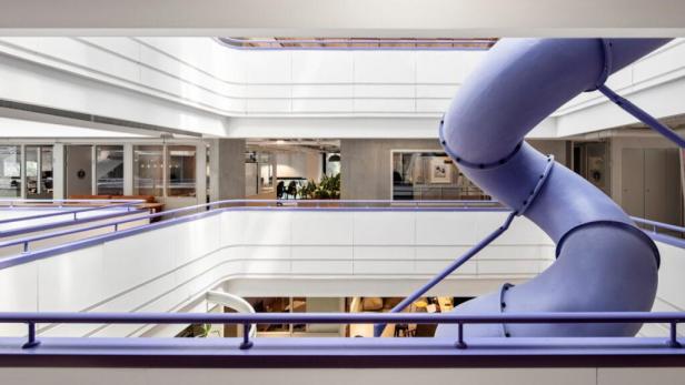 Eine lila Rutsche schlängelt sich durch das Innere eines mehrstöckigen Gebäudes.