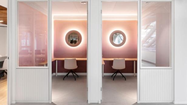 Zwei moderne Arbeitskabinen mit Schreibtischen und Stühlen in einem Büro.