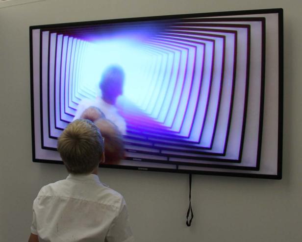 Eine Person betrachtet einen Fernseher mit einer Tunnel-artigen Grafik.