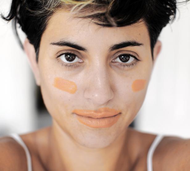 Eine Frau mit Make-up-Flecken im Gesicht und auf den Lippen blickt in die Kamera.