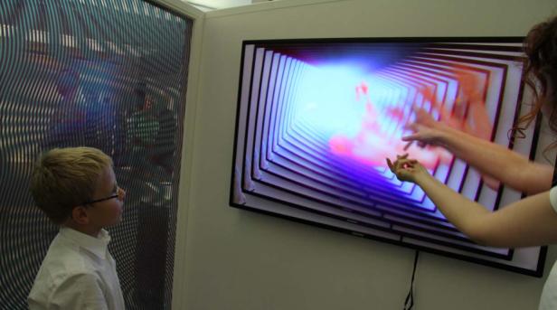 Ein Junge mit Brille betrachtet eine interaktive Kunstinstallation.