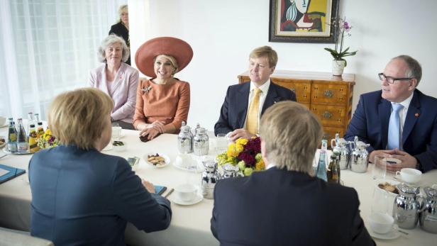 König Willem-Alexander und Königin Máxima der Niederlande sitzen mit anderen an einem Tisch.
