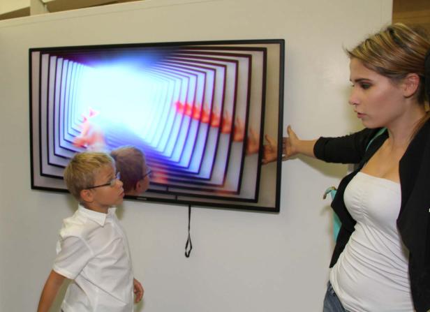 Ein Junge und eine Frau betrachten ein interaktives Kunstwerk auf einem Bildschirm.