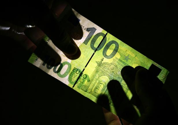 Ein 100 Euro-Schein der gegen das Licht gehalten wird.