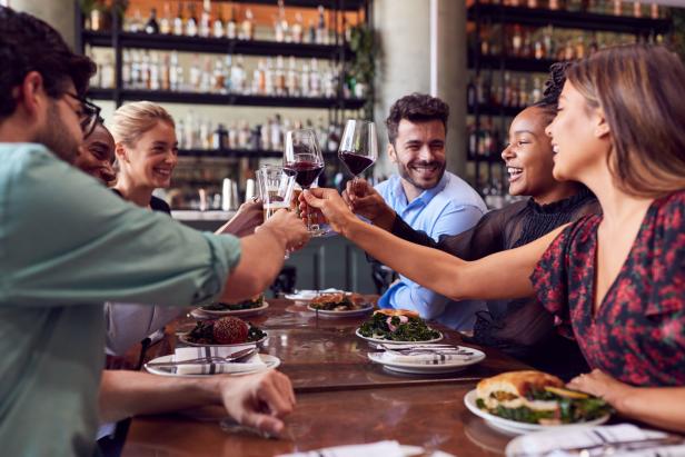 Eine Gruppe von Freunden stößt in einem Restaurant mit Wein- und Biergläsern an.