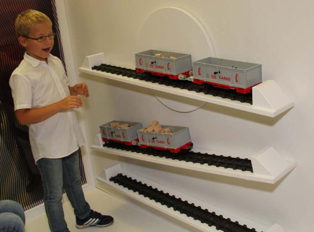 Ein Junge betrachtet eine Spielzeugeisenbahn an der Wand.