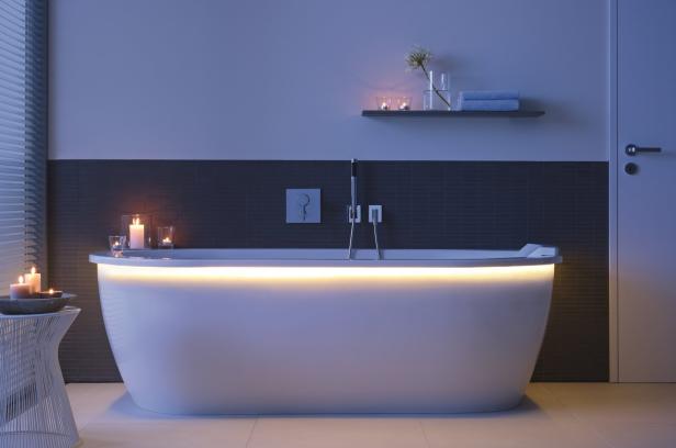 Ein Badezimmer mit einer freistehenden Badewanne, die von unten beleuchtet wird.