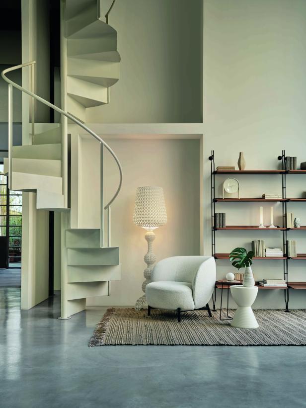 Ein Wohnzimmer mit einer Wendeltreppe, einem Sessel und einem Bücherregal.
