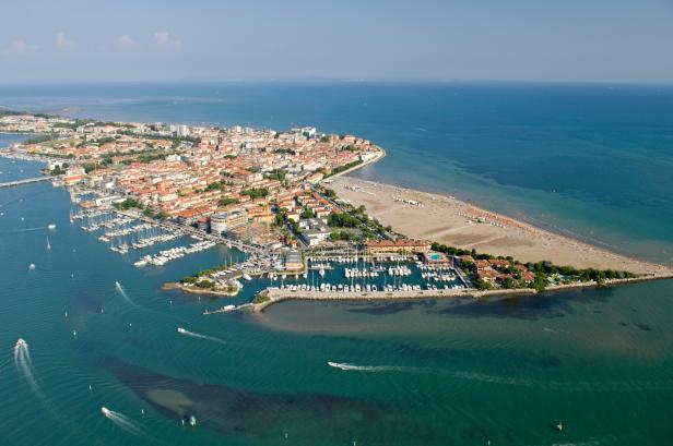 Luftaufnahme von Grado, Italien, mit Yachthäfen und Strand.