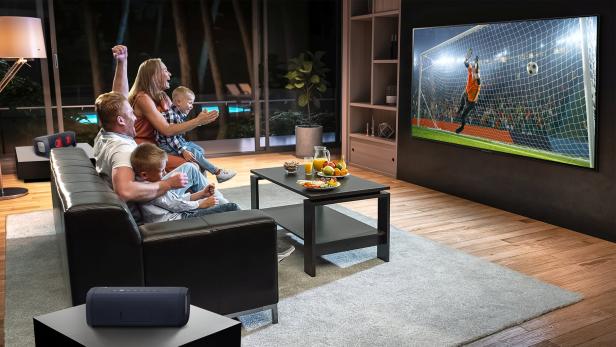 Eine Familie schaut begeistert ein Fußballspiel im Fernsehen.