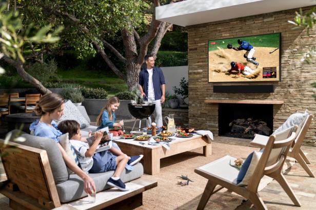 Eine Familie genießt ein Barbecue im Freien und schaut Baseball im Fernsehen.