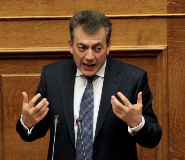 Ein Mann in einem Anzug gestikuliert vor einem Mikrofon.