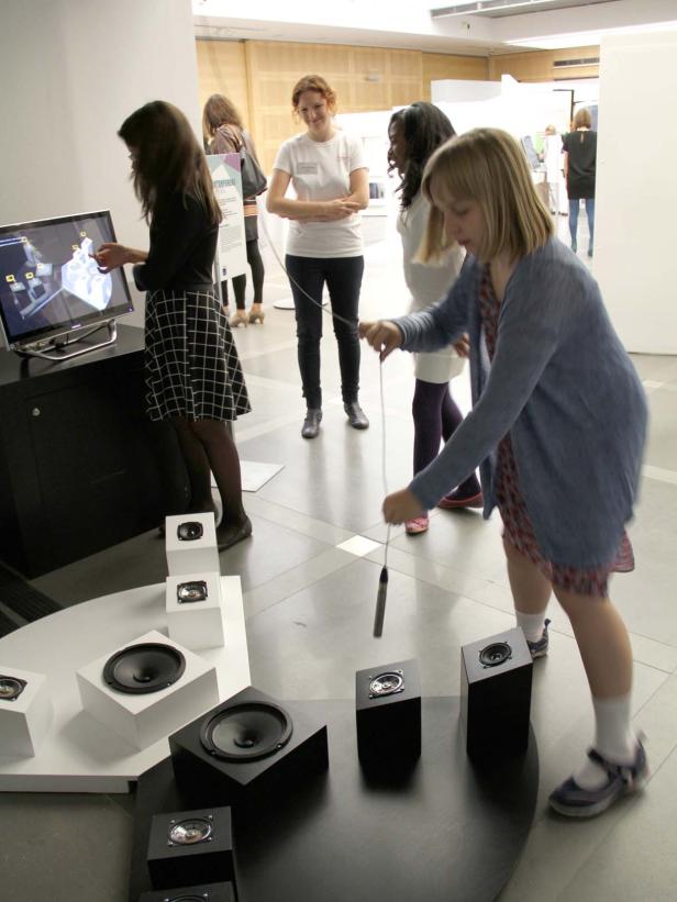 Besucher interagieren mit einer Klanginstallation mit Lautsprechern und einem Bildschirm.