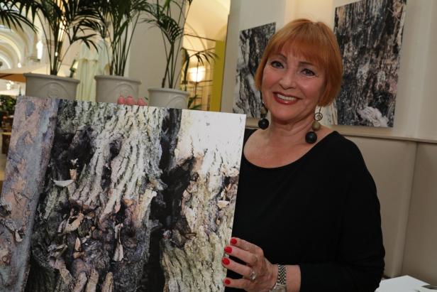 Eine Frau hält ein Foto von einer Baumrinde in der Hand.
