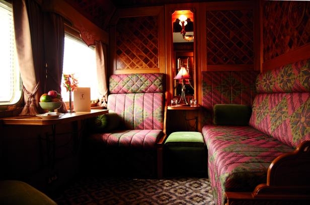 Das Interieur eines luxuriösen Zugabteils mit floralen Mustern und Holztäfelung.
