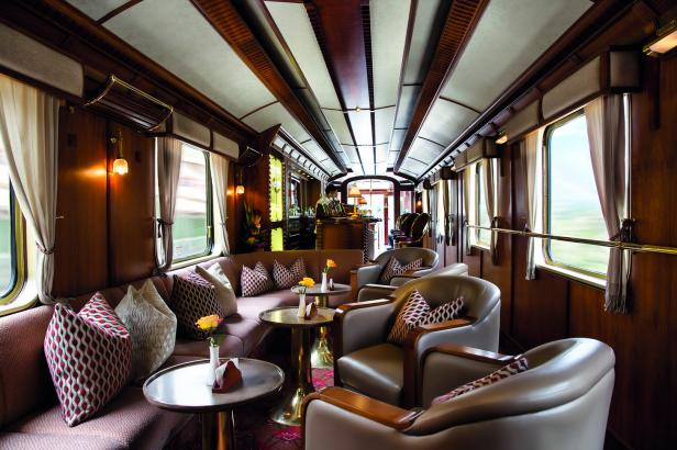 Innenansicht eines luxuriösen Zugwaggons mit Sitzgelegenheiten und Bar.