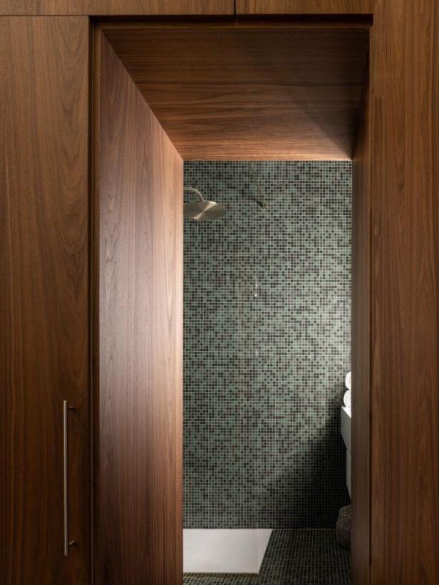 Ein Badezimmer mit dunklen Mosaikfliesen und einer Holztür.