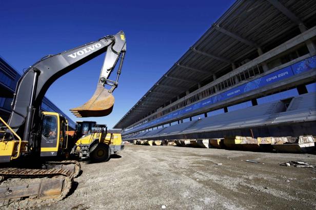 Ein Volvo-Bagger steht vor einem Stadion mit der Aufschrift „Sotschi 2014“.