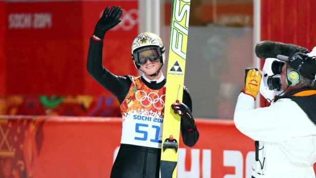 Ein Skispringer mit Startnummer 51 winkt in die Kamera.