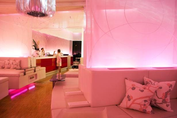 Ein rosa beleuchteter Innenraum mit Sitzgelegenheiten und einer Bar im Hintergrund.