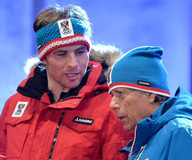 Zwei Männer, vermutlich österreichische Sportler, tragen Winterkleidung mit dem österreichischen Wappen.