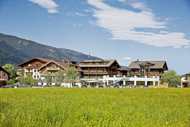Ein Hotel in den Bergen mit einer blühenden Wiese im Vordergrund.