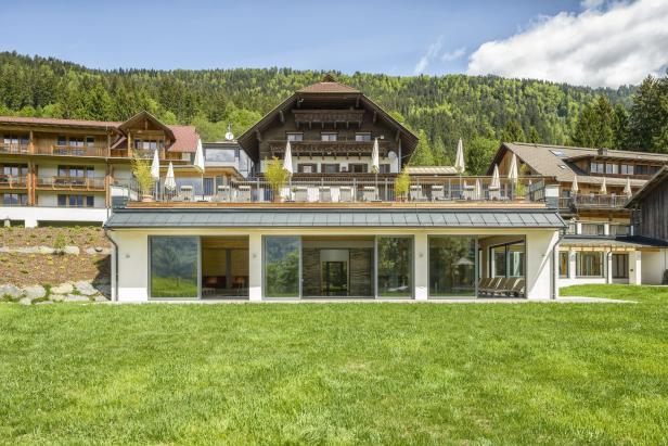 Ein großes Hotel mit mehreren Gebäuden vor einem bewaldeten Hügel.