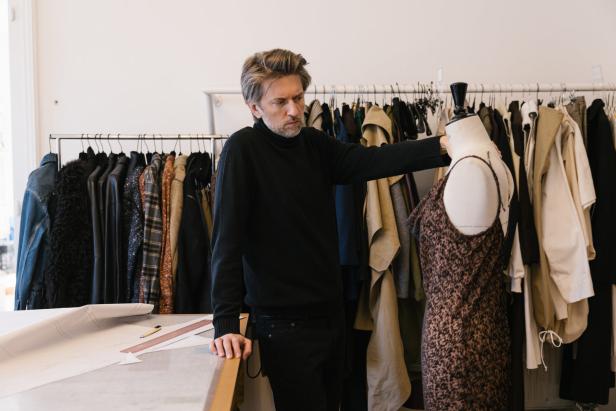 Ein Modedesigner drapiert ein Kleid auf einer Schneiderpuppe in seinem Atelier.