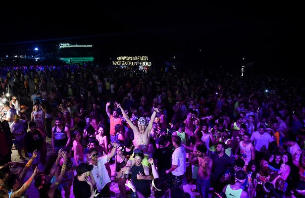 Eine große Menschenmenge feiert eine Strandparty bei Nacht in Koh Phangan.