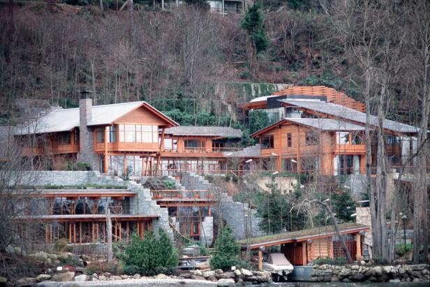 Ein großes Holzhaus mit vielen Fenstern an einem bewaldeten Hang.