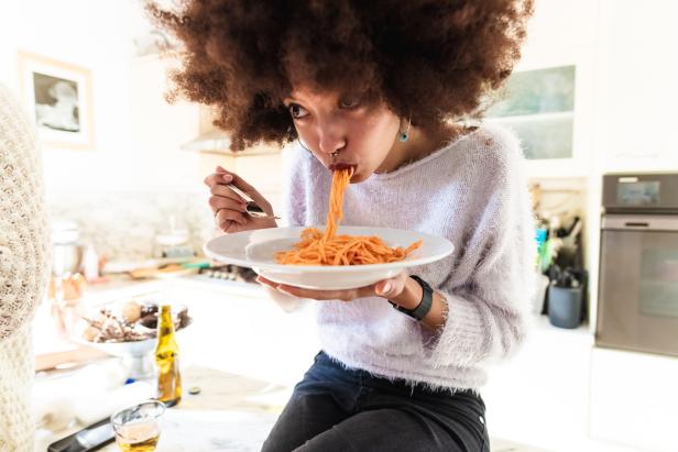 Eine Frau mit Afro-Frisur isst Spaghetti mit Tomatensoße.