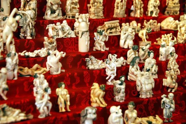 Eine Sammlung von Elfenbeinfiguren auf einem roten Tuch mit asiatischen Motiven.