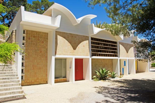 Das moderne Haus mit roter Tür hat eine Fassade aus hellbraunen Fliesen.