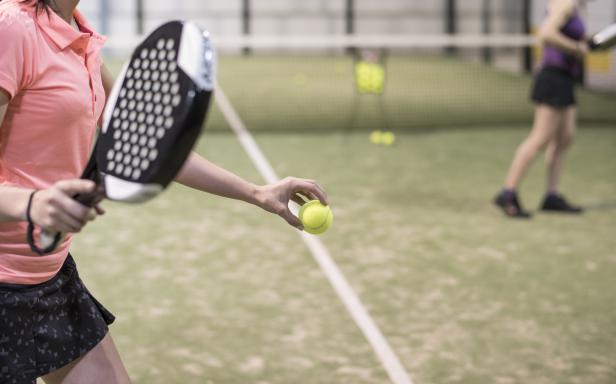 Eine Frau bereitet sich auf einem Padel-Platz vor, den Ball zu servieren.