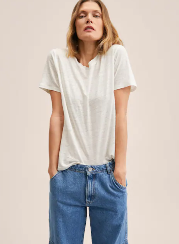 Eine Frau trägt ein weißes T-Shirt und blaue Jeans.
