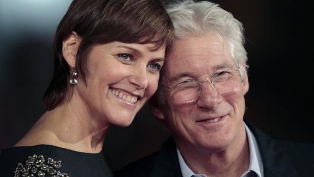Richard Gere posiert mit einer Frau auf einem roten Teppich.